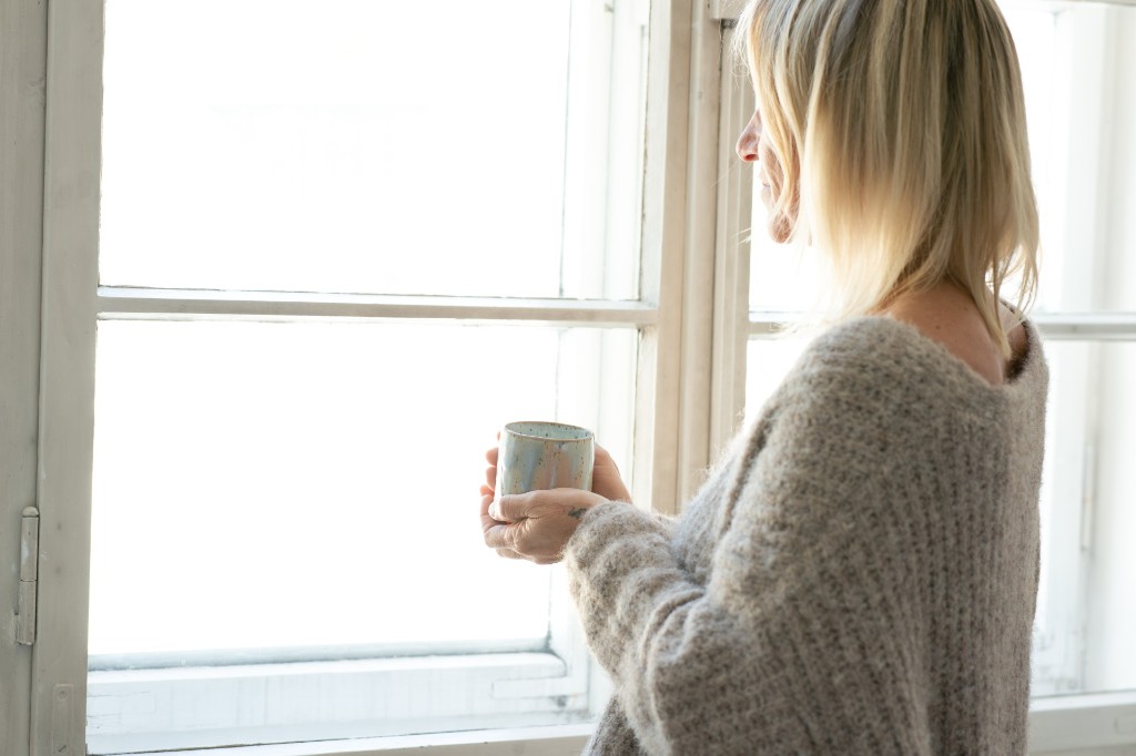 Stefanie Kneidinger steht mit einer Tasse am Fenster