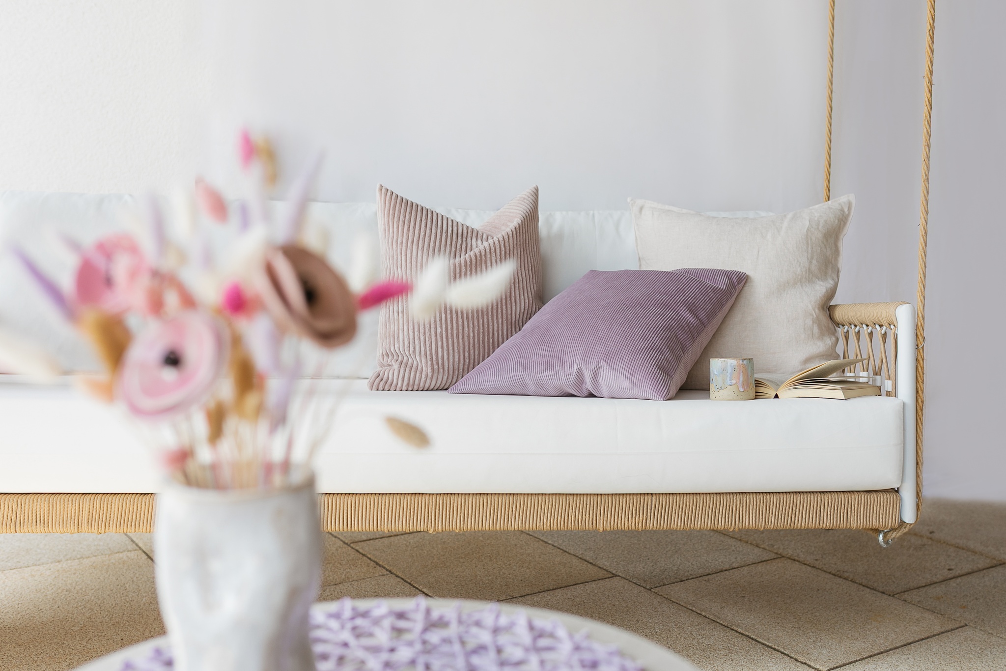 Ein ruhiger Raum mit Sofa, Kissen und getrockneten Blumen – ein Ort der Geborgenheit