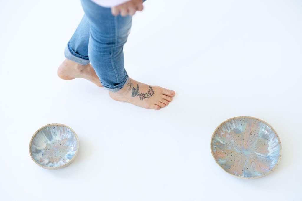 Barfuße Füße mit Schmetterling-Tattoo und handgefertigten Keramikschalen