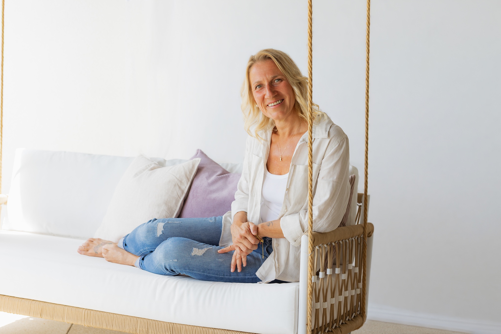 Stefanie Kneidinger sitzt lächelnd auf einem Hängesofa in einem hellen, ruhigen Raum